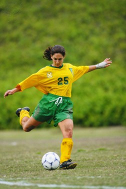 A soccer player using the form to kick the soccer ball.